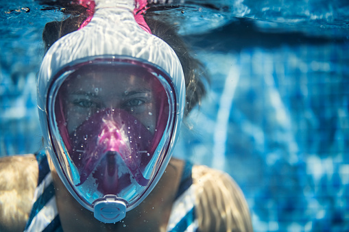 Happy teenage girl swimming underwater in the pool. The girl is wearing a modern full-face snorkel mask.
Canon R5
