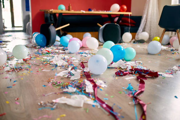 After party chaos, messy in livving room at home After party chaos, messy in livving room at home, table with pizza and champagne glasses covered with confetti and ballons, chair on the floor at morning after party celebration. after party stock pictures, royalty-free photos & images