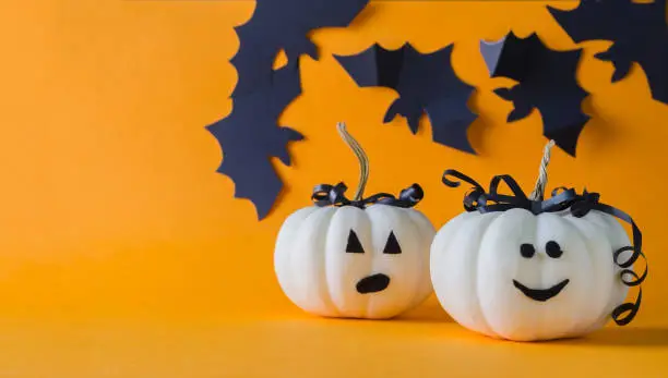 Photo of Halloween holiday. Two white pumpkins on an orange background, minimalism