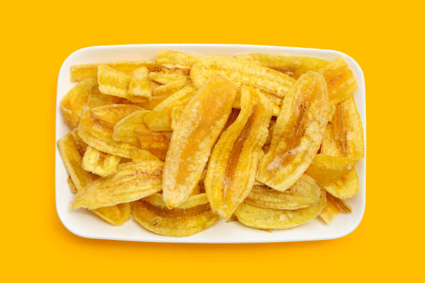 istock Banana slice chips in white plate on yellow background 1339198849