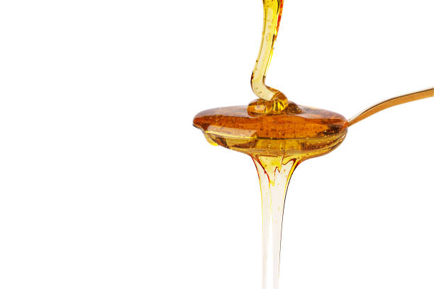 istock Honey dripping on spoon isolated on white background. 1339198880