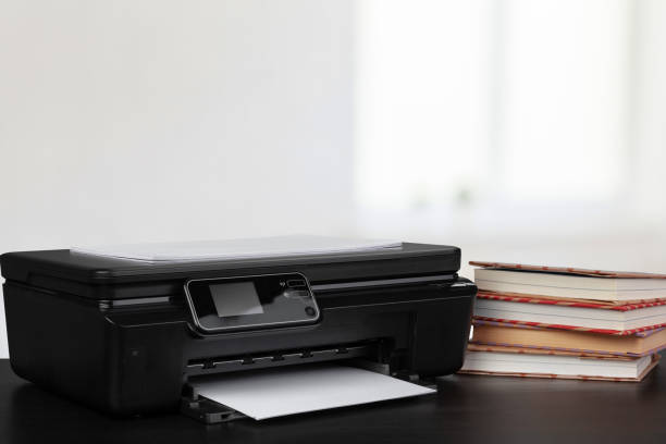 istock Compact home printer on desk with books against blurred background 1339201196