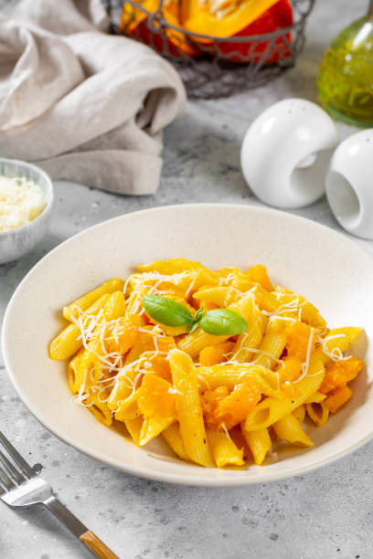 istock Neapolitan pasta penne rigate with pumpkin in a ceramic plate on a light gray culinary background close-up. Traditional Italian cuisine 1339201973
