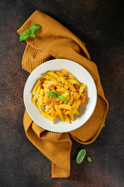 istock Neapolitan pasta penne rigate with pumpkin in a ceramic plate on a dark culinary background top view. Traditional Italian cuisine 1339201974