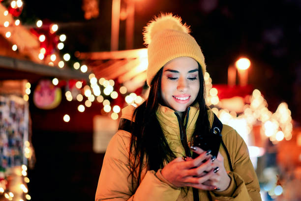 istock Happy young woman using phone at the Christmas bazaar 1339202194