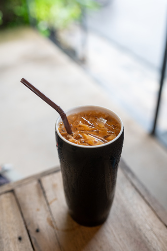 Image of Iced milk tea or Thai milk tea in glass on the table.\nThai Ice milk tea, traditional Thai style in country side coffee shop.