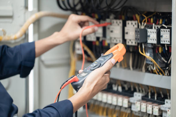 Electrician engineer work tester measuring voltage and current of power electric line in electrical cabinet control , concept check the operation of the electrical system . stock photo