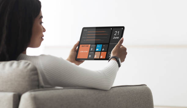 istock Black woman holding digital tablet with smart home app 1339211254