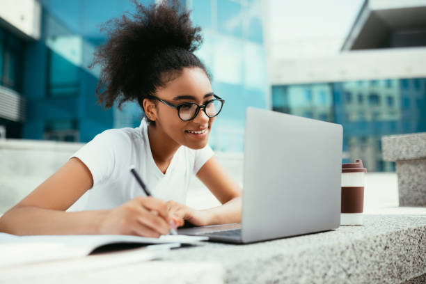 istock Happy Black Student Girl Doing Homework Using Laptop Outdoor 1339211373