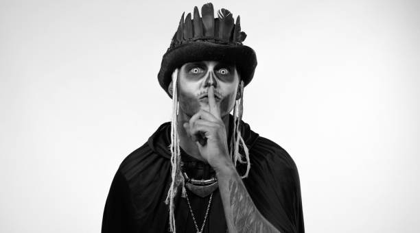 istock Creepy man with skeleton makeup asking to stay calm, keep silence with finger on lips gesture 1339212631