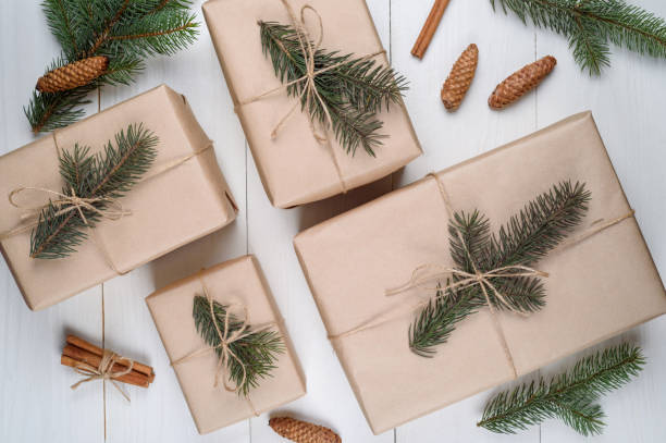 istock Christmas background with gift boxes wrapped in kraft paper with fir tree branches and cones on white wooden background, free space. Holiday greeting card, copy space. Flat lay, top view 1339215703