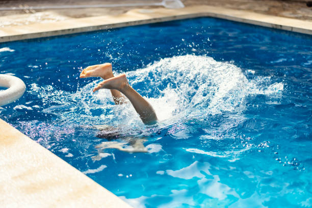 Teenage girl jumping into swimming pool on summer day. stock photo