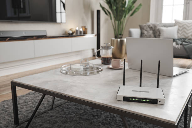 интернет-роутер и ноутбук на журнальном столике в современной гостиной с размытым фоном - router стоковые фото и изображения