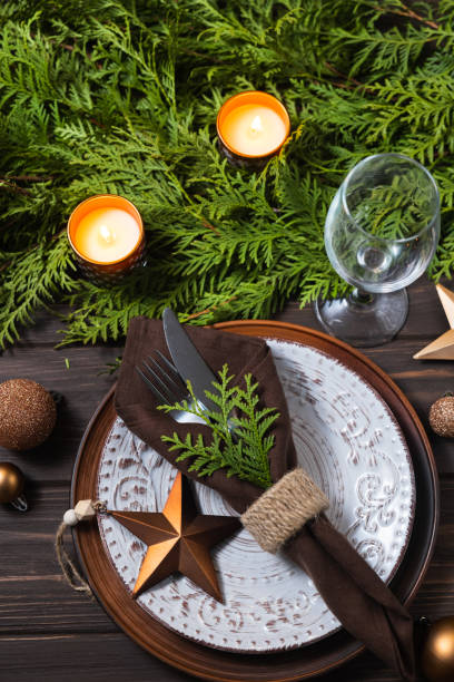 istock Festive table setting with Christmas decorations, fir branches and candles on wooden background. 1339224335