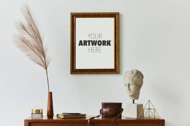 istock Stylish composition of artist workspace room with design retro teak commode, mock up poster frame, book, decoration and painting accessories. Template. 1339234963