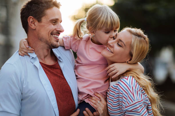 Sunshine and smiles Affectionate young parents and her little daughter three way kiss stock pictures, royalty-free photos & images