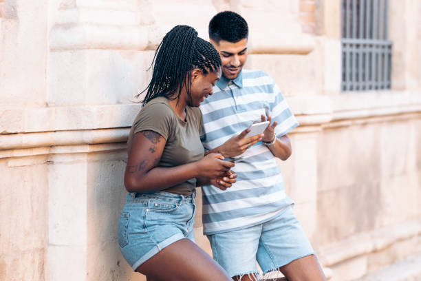 istock Two young people leaning on a wall in the street while using the mobile 1339239859