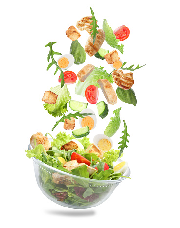 Fresh ingredients for tasty salad falling into bowl on white background