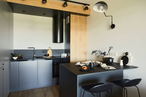 istock Stylish composition of modern kitchen and dining room interior in small apartment. Black furniture, kitchen island and wooden kitchen accessories. Creative wall. Template. 1339241829