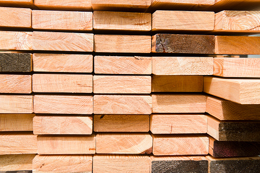 Stack of larch wood planks for a new boardwalk. Stack with small wooden strips between the planks so that they can dry out well.