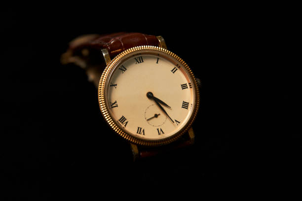 Men's wrist watch on dark background, close-up. Luxury gold wrist watch with brown leather strap