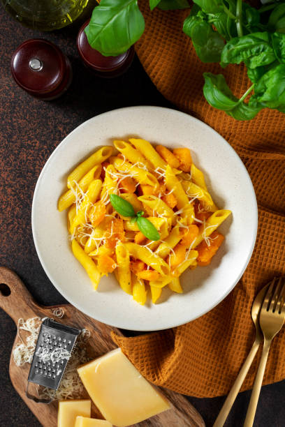 istock Neapolitan pasta penne rigate with pumpkin in a ceramic plate on a dark culinary background top view. Traditional Italian cuisine 1339246945