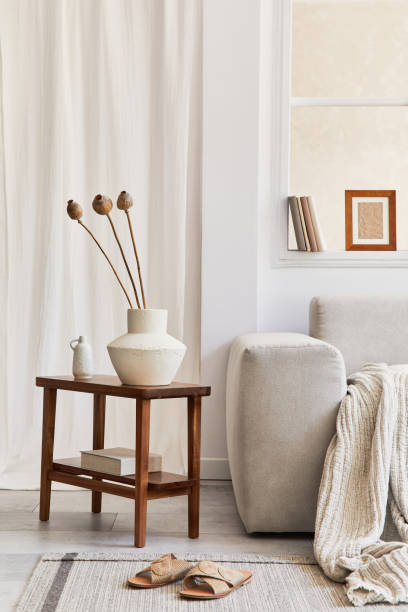 istock Creative composition of stylish and cozy living room interior with mock up frame, grey corner sofa, window, dried flowers on coffee table and personal accessories. Beige neutral colors. Template. 1339247075