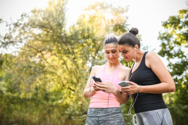 istock Smiling Female Athletes Exchanging Workout Playlists With Smartphones 1339248823