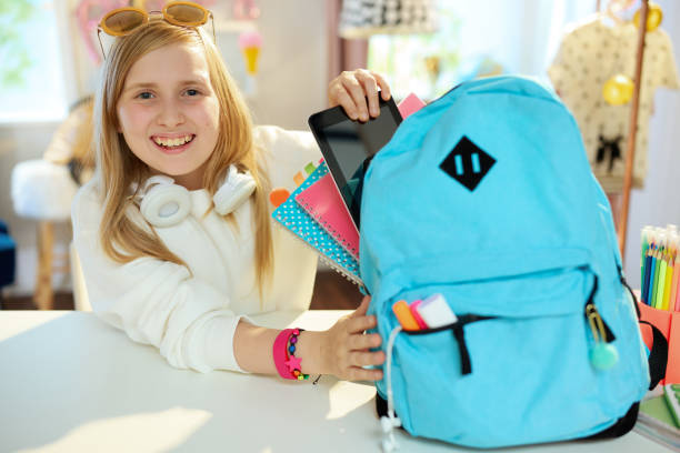istock smiling modern pupil packing for school at home in sunny day 1339250903