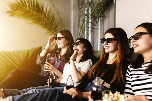 Photo of Group of people are watching a movie. Friend girls eat popcorn and drink soda