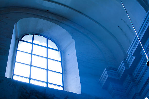 Arched stained glass window with cross pattern in a church facade