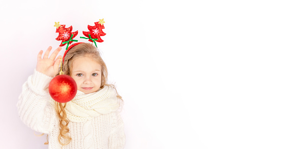 baby girl holding a red Christmas ball on a white isolated background, space for text, banner