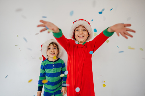 Photo of two young boys, being festive on Christmas morning. Boys are throwing confetti while still in pyjamas.