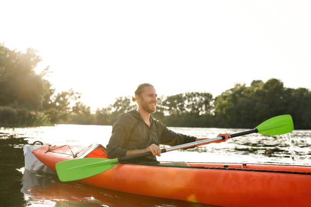 istock Cheerful young man kayaking on river, holding paddle, smiling away on a summer day 1339258370