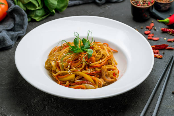 istock Udon noodles with chicken and vegetables on white plate on black stone table 1339264170