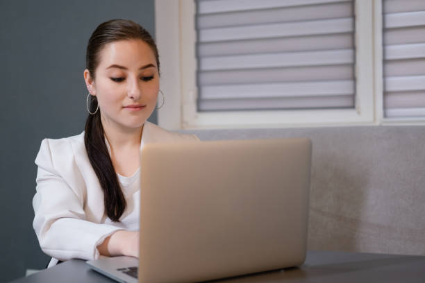 istock brunette woman use laptop in grey room. freelancer. working from home. student, remote study 1339264661