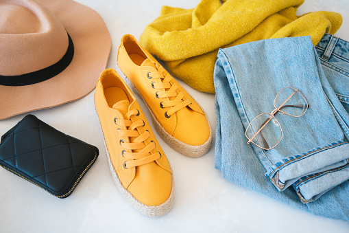 Flat lay with woman's clothes and accessories: jeans, sneakers, sweater and fedora hat