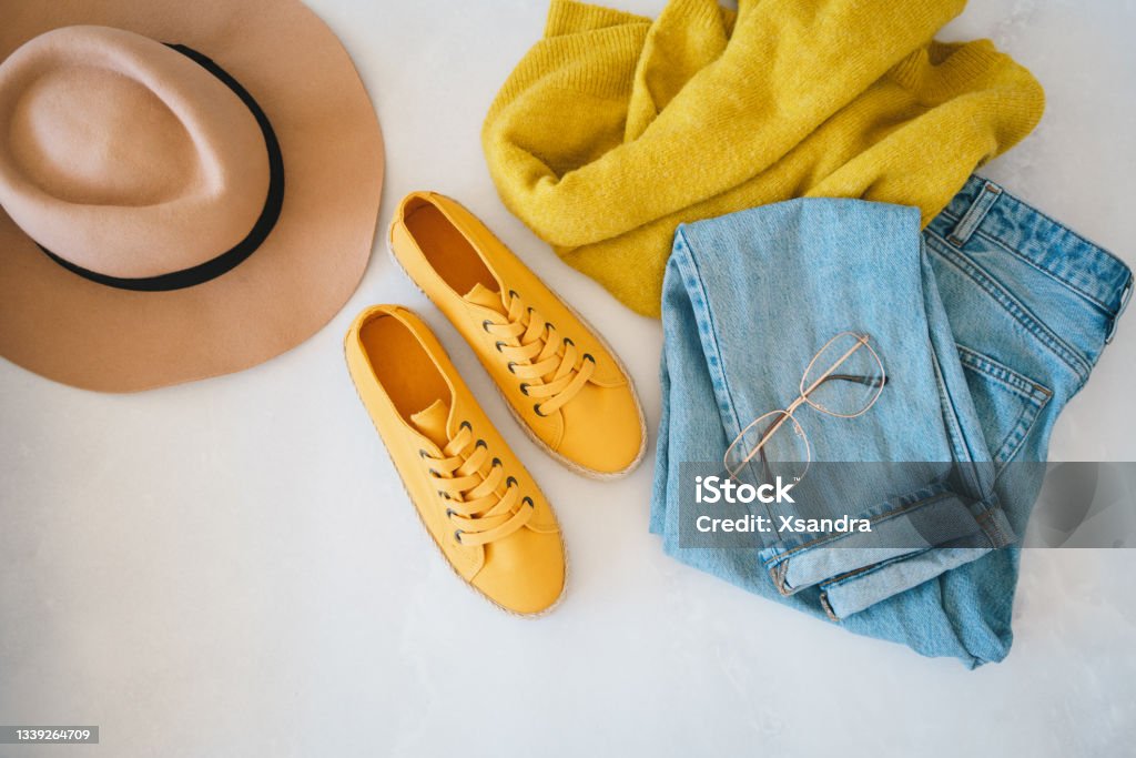 Flat lay with woman's clothes and accessories Flat lay with woman's clothes and accessories: jeans, sneakers, sweater and fedora hat Clothing Stock Photo