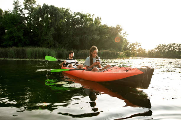 istock Young couple relaxing together, kayaking on the river. Woman using her smartphone while resting 1339266472