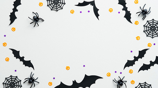 Happy Halloween holiday concept. Halloween decorations on white background. Flat lay, top view spiders, web, bats, confetti.