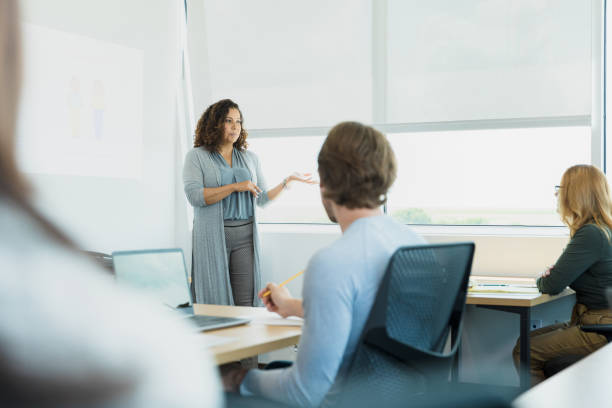 istock Female teacher gestures while lecturing to adult class 1339268539