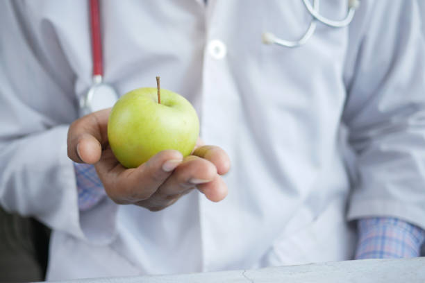 istock doctor's hand holding green apple while sited 1339271472