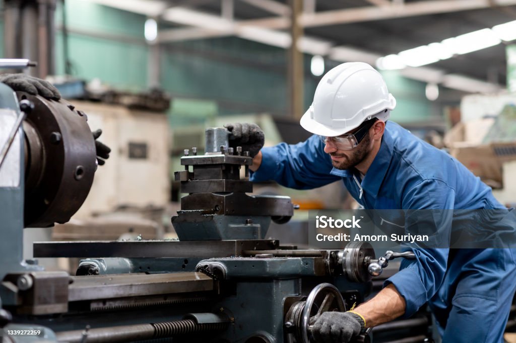 Industrial engineer worker in white hard hat working with production machinery in the factory Lathe Stock Photo