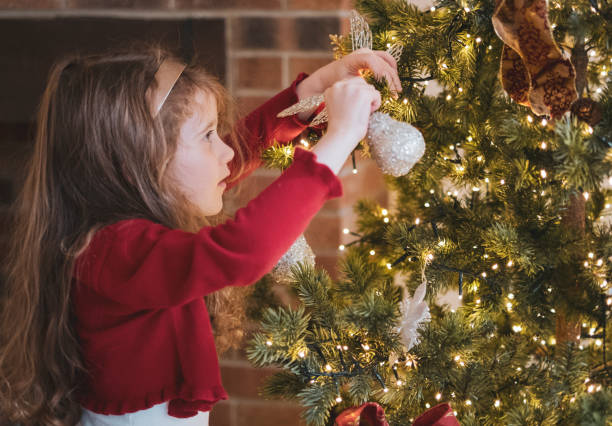 istock Little Girl Decorating Christmas Tree with Ornaments 1339273222