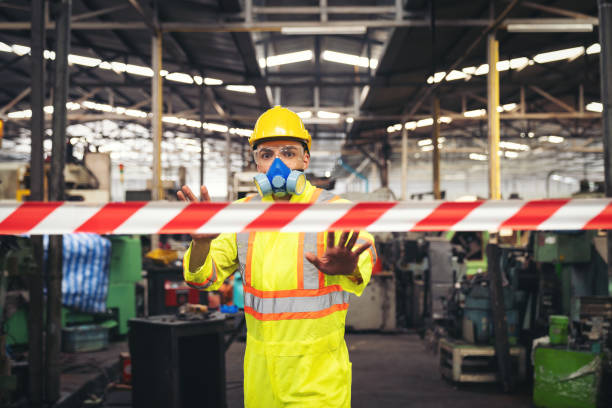 化学専門家は、ラインエリアバリア赤と白の色の後ろに立っている間、彼の手が業界工場で侵入化学物質の危険な領域を示さない示す安全制服とガスマスクを着用します - chemical accident ストックフォトと画像