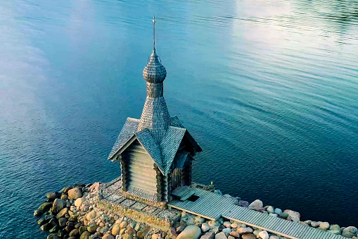 A small wooden chapel on a rocky shore, shooting from a drone.