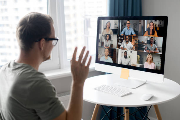 istock Attentive young hipster man involved virtual meeting sitting at table with PC 1339286107