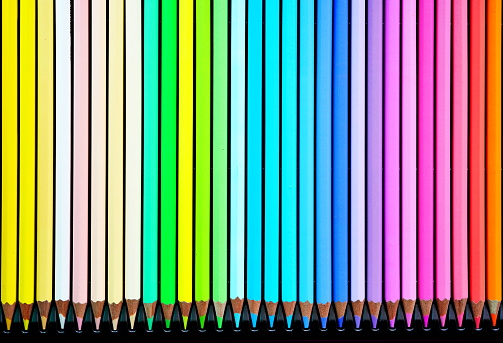 Wooden colored pencils lined up in a row background