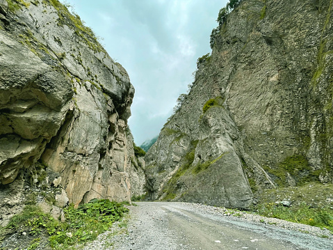 A road meandering between rocks in the narrow Karmadon Gorge in Caucasus mountains, North Ossetia, Russia