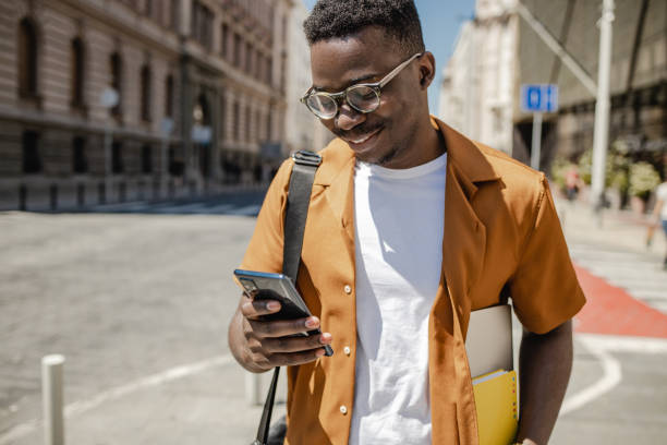 istock African-American confident young man is using mobile phone on the street 1339291778